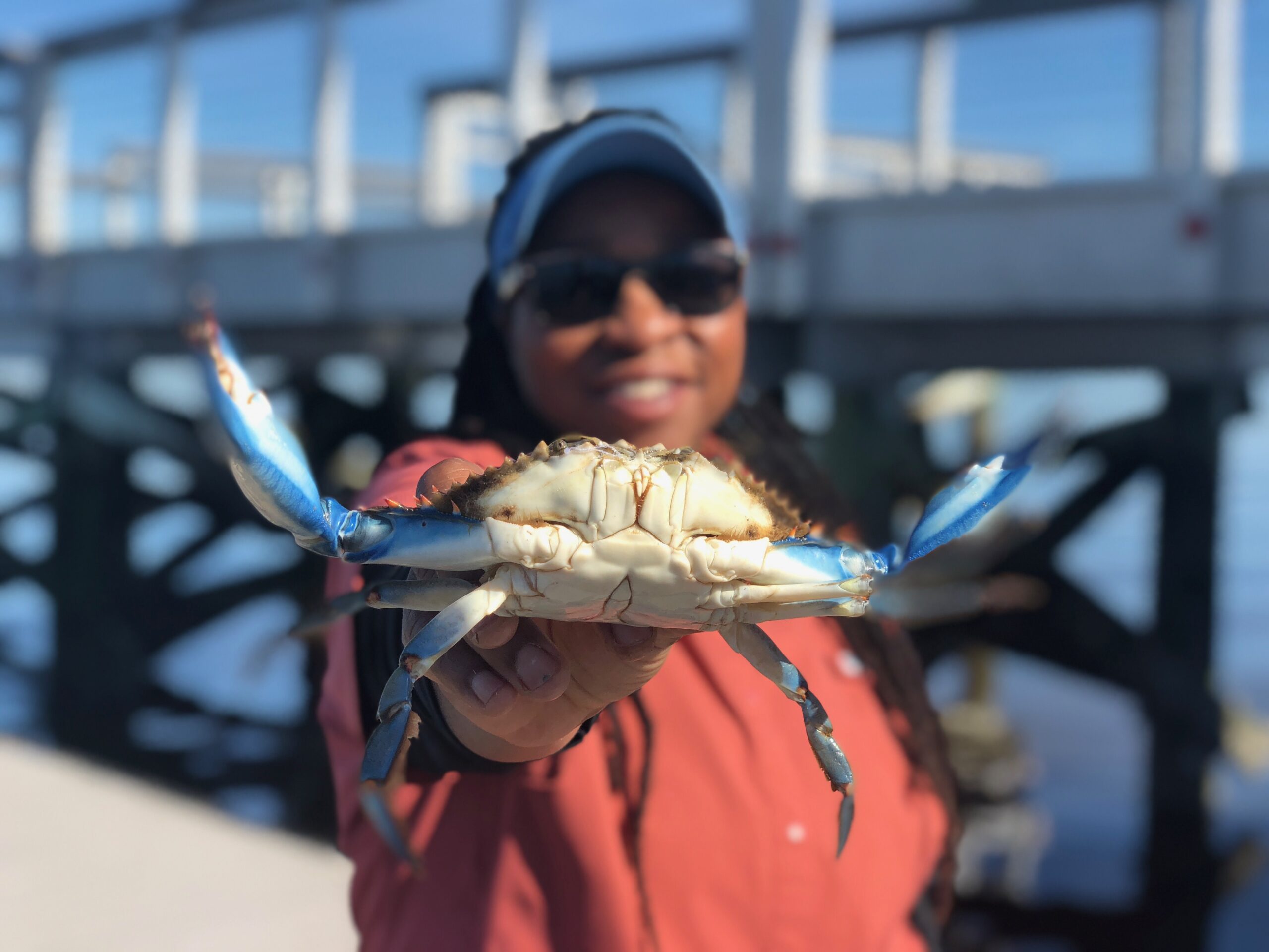 Casual Crabbing with Tia brand image: A woman holds a blue crab close to the camera.