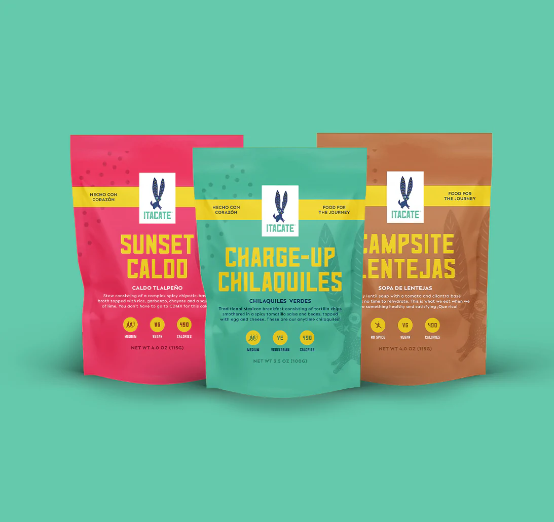 Three pouches of backpacking food in bright and colorful packaging.