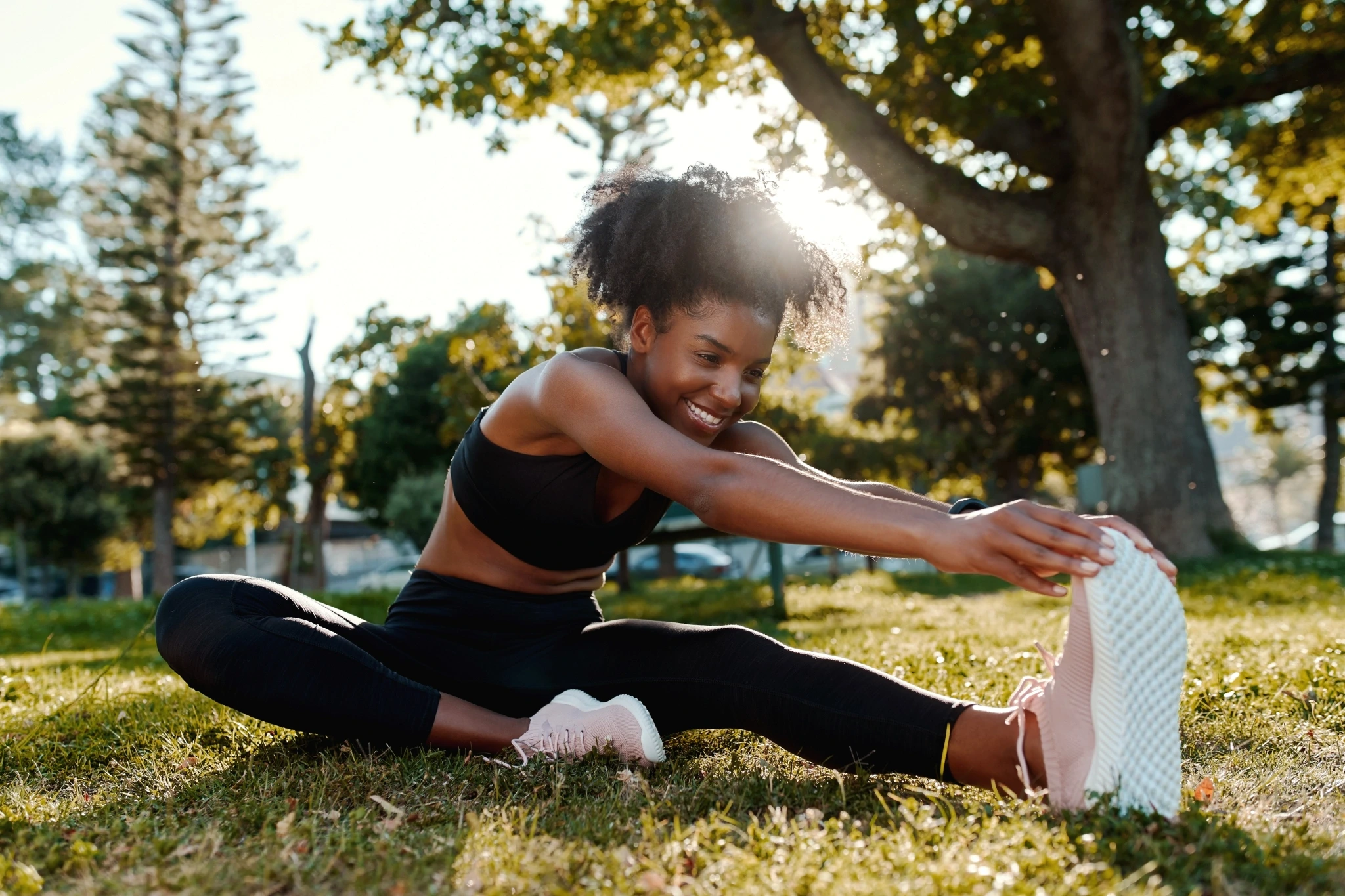 a woman stretches her hamstring while seated in an outdoor setting
