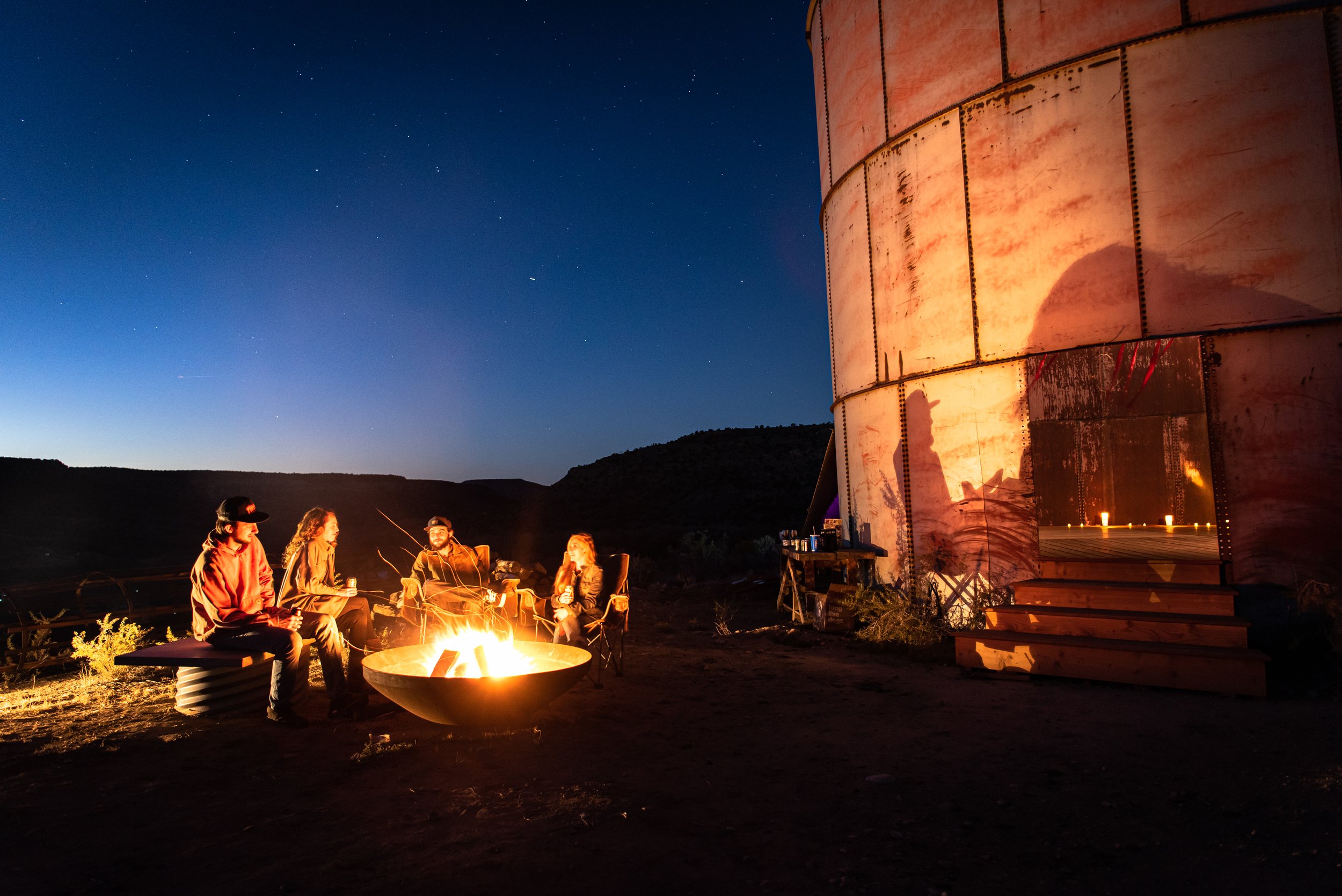 people gather around a fire outside at night