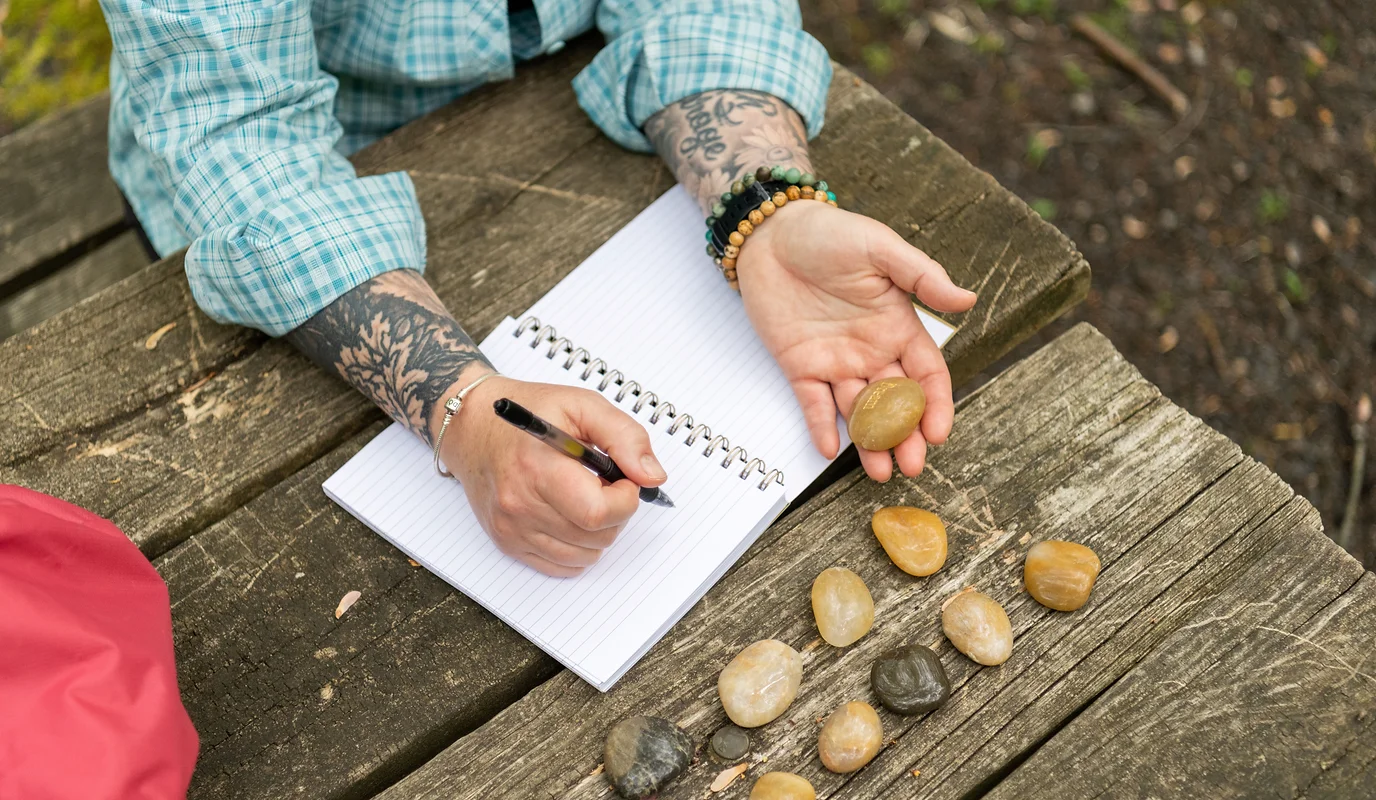an overhead shot of hands with a journal and pen and a collection of rocks