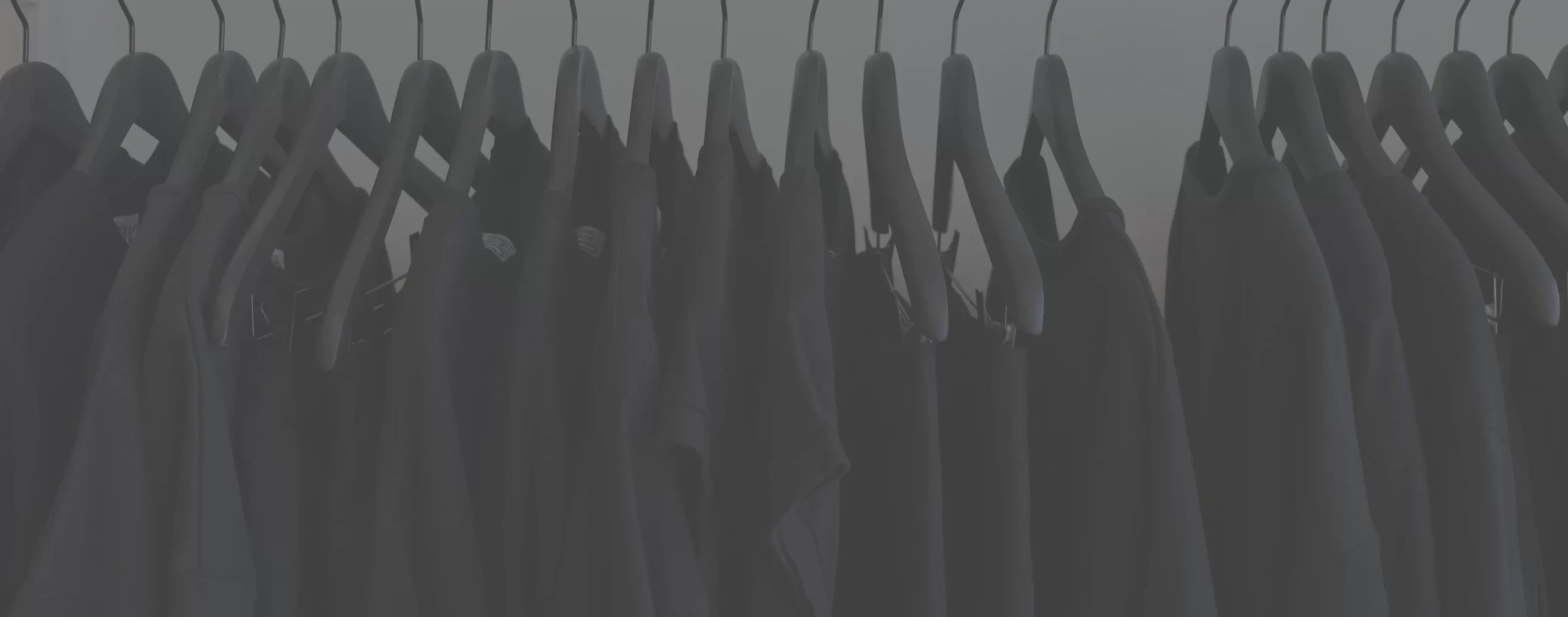 a row of dark garments are hanging on a rack